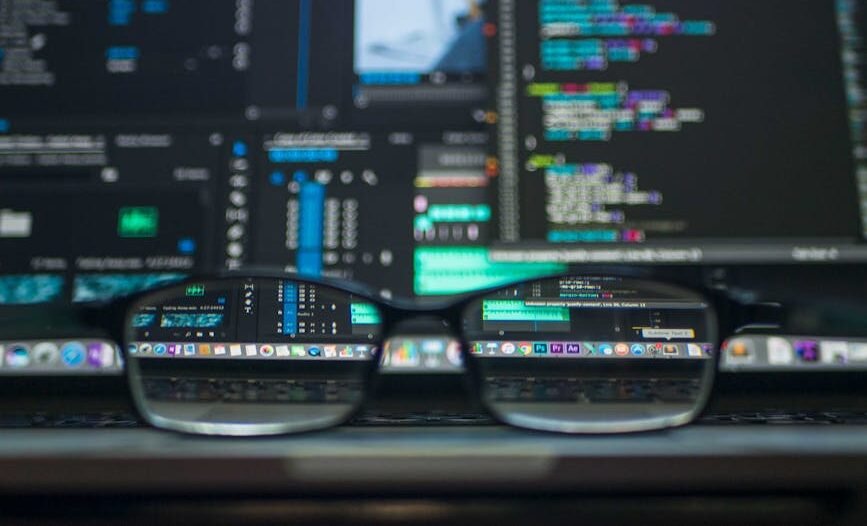 Eyeglasses reflecting computer code on a monitor, ideal for technology and programming themes.