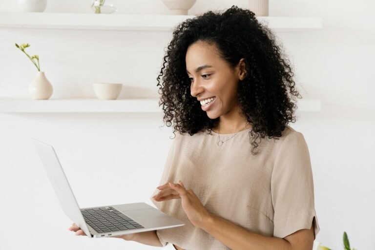 Smiling woman working on a laptop in a modern home office, highlighting freelance lifestyle.